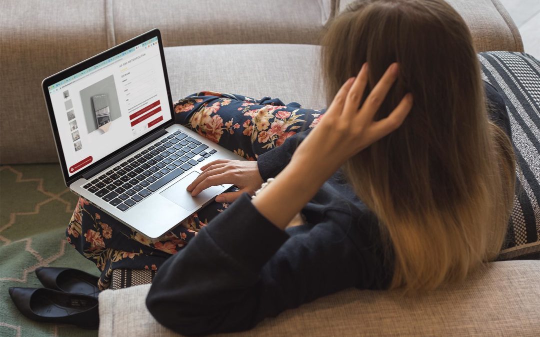 The back of a woman sitting on a couch with a laptop on her lap, browsing an online paint store, with the paint color AF-690 Metropolitan on her screen.